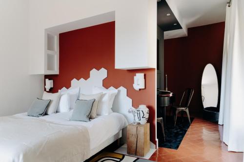 a bedroom with a white bed with a red wall at Hôtel Domaine de Biar in Montpellier