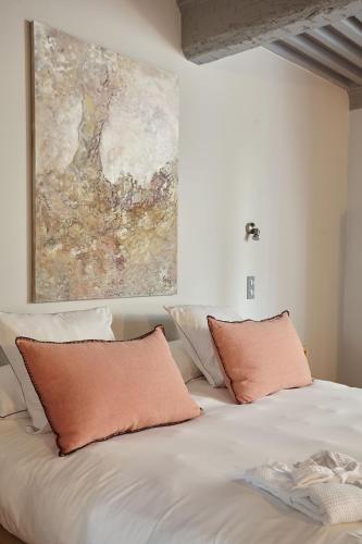 a bed with two pillows and a painting on the wall at Boutique Hôtel Entraigues in Uzès