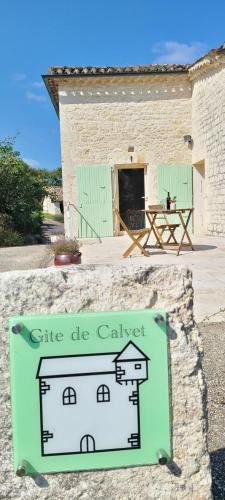 a sign in front of a building with a table at Petit Gîte de Calvet in Sainte-Croix
