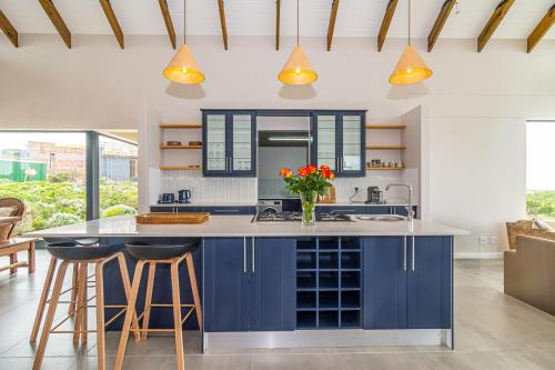 a kitchen with blue cabinets and a counter with stools at Fynbos Barn in Gansbaai