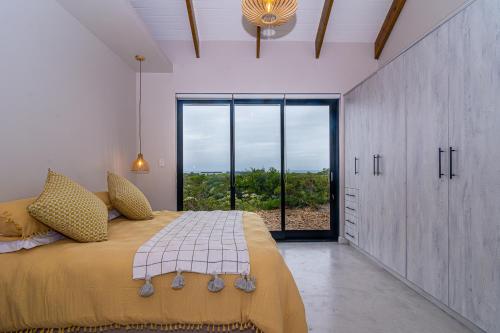 a bedroom with a large bed with a large window at Fynbos Barn in Gansbaai