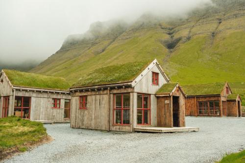 a building with grass on the roof with a mountain at Múlafossur Cottages by famous waterfall in Gásadalur in Gásadalur