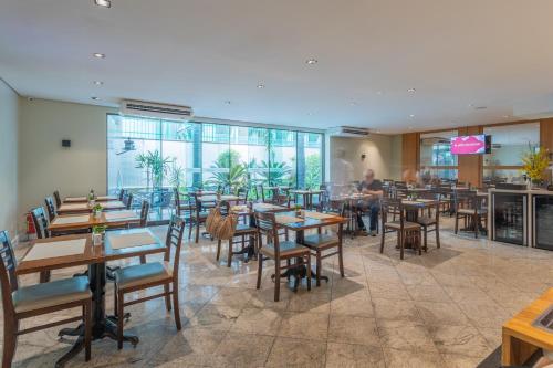 a restaurant with tables and chairs and people in the background at Green Place Ibirapuera in São Paulo
