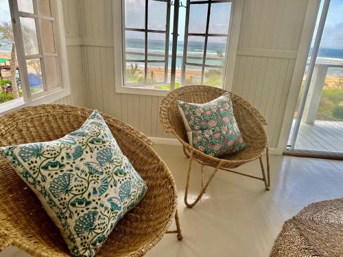 two wicker chairs with pillows in a room with windows at Villa de Surf in Ponta do Ouro