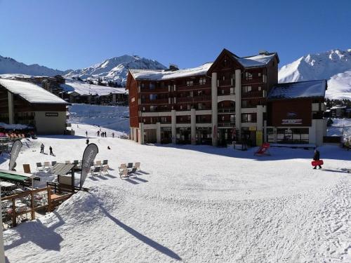 un lodge de ski sur une piste enneigée avec des personnes dans l'établissement Appartement cosy au cœur de Plagne Soleil, accès direct pistes, 5 pers, balcon, casier à ski - FR-1-351-132, à La Plagne Tarentaise