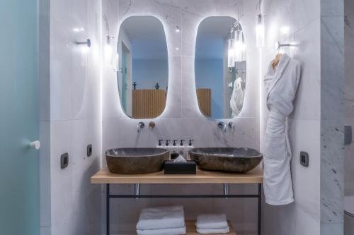 a bathroom with two sinks and a mirror at Cayo Exclusive Resort & Spa in Elounda