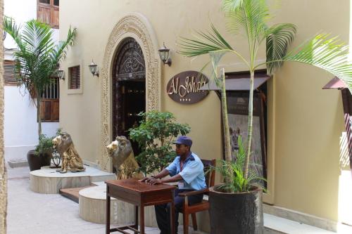a man sitting at a table in front of a building at Al Johari in Zanzibar City