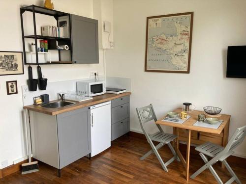une cuisine avec un évier et une table avec des chaises dans l'établissement Studio cosy, lumineux et bien situé, à Lorient