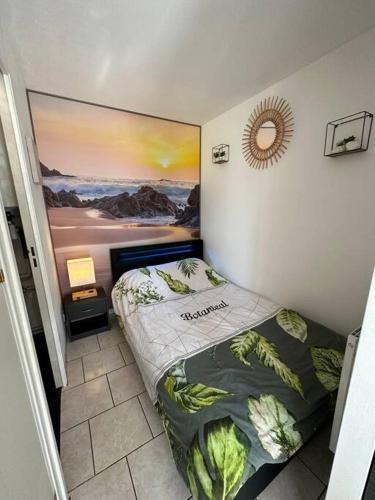 Cette petite chambre comprend un lit avec une photo murale. dans l'établissement Aux accents maritime et jardin 200m de la mer, à Merville-Franceville-Plage
