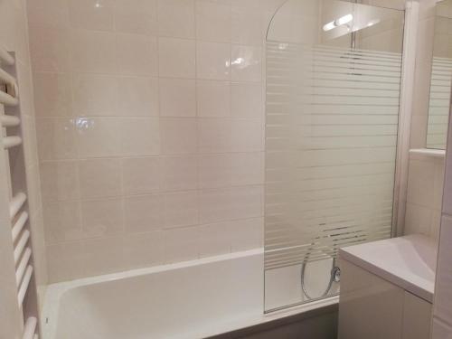 une salle de bain blanche avec une baignoire et une douche dans l'établissement Appartement cosy à Plagne Village avec accès direct aux pistes, terrasse exposée sud, animaux acceptés - FR-1-351-22, à La Plagne