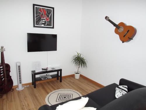 a living room with a couch and a guitar on the wall at The Music House, Ilha Terceira, Açores in Praia da Vitória