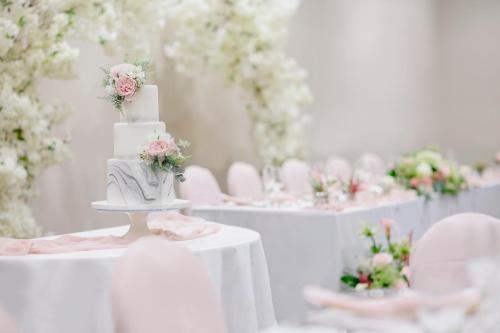 a white wedding cake on a table with roses at Holiday Inn Leicester City by IHG in Leicester