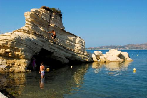 a man standing in the water next to a cave in the water at Vanessa Hotel in Kalamaki