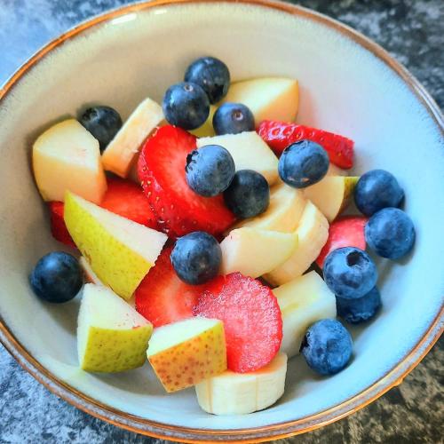 a bowl filled with fruit and berries on a table at Swallows Nest Plett in Plettenberg Bay