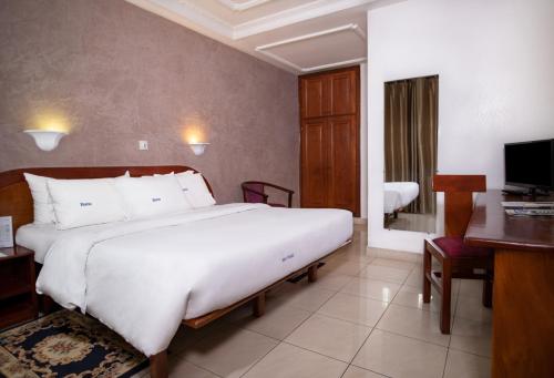 a bedroom with a large bed with a desk and a computer at Bano Palace Hotel in Douala