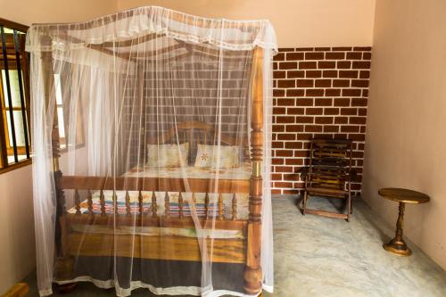 a bedroom with a bed with a net curtain at Sunshadow Chalet in Tangalle