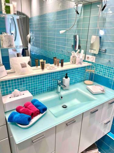 La salle de bains est pourvue d'un lavabo et d'un mur carrelé bleu. dans l'établissement Un écrin de verdure aux portes de Paris, à Bry-sur-Marne