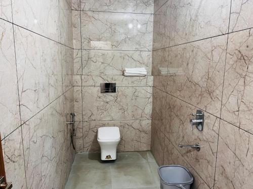 a bathroom with a toilet and a tiled wall at Hotel Hare Krishna Dham in Vrindāvan