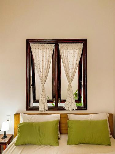 a bedroom with a window with two green pillows at DƯỚI TÁN CÂY homestay in Tây Ninh