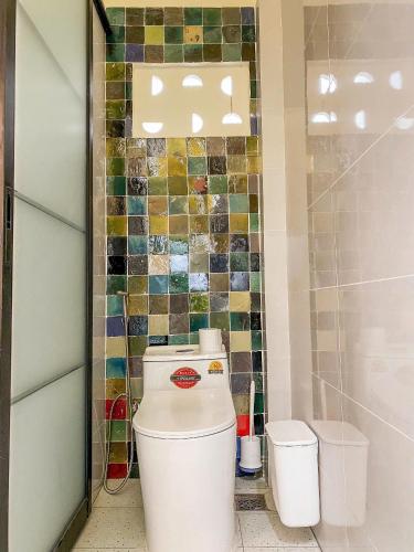 a bathroom with a toilet and a mosaic wall at DƯỚI TÁN CÂY homestay in Tây Ninh