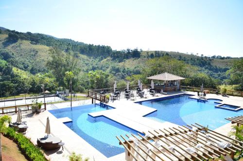 a large swimming pool with chairs and a gazebo at Hotel Chalés Capitanias in Águas de Lindóia