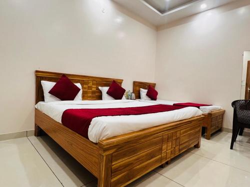 a bedroom with a large wooden bed with red pillows at Hotel Hare Krishna Dham in Vrindāvan