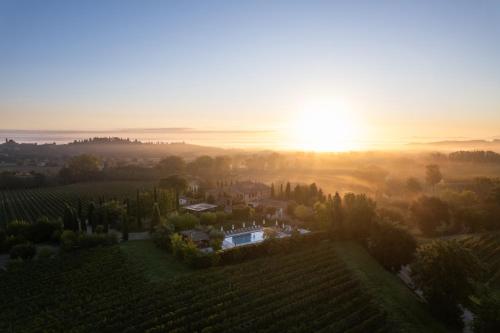a house in a vineyard with the sunset in the background at Borgo San Vincenzo in Montepulciano