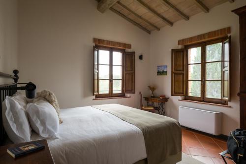 a bedroom with a white bed and two windows at Borgo San Vincenzo in Montepulciano