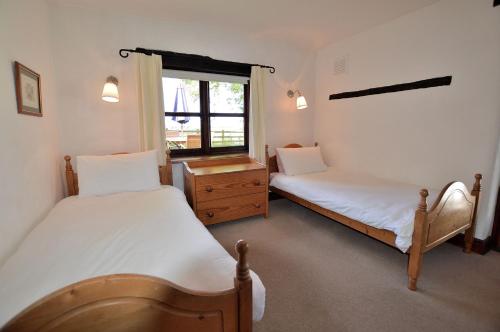 two beds in a room with a window at The Smithy nr Huntsham in Tiverton