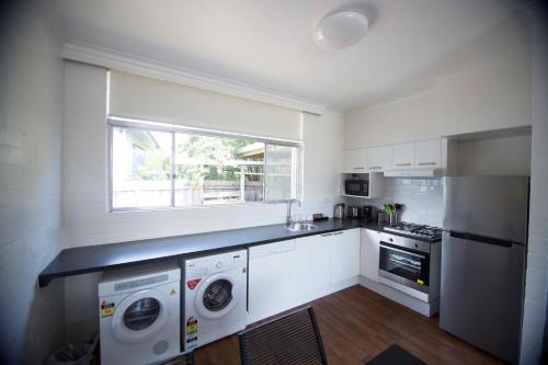 una cucina bianca con lavatrice e asciugatrice di Siesta Central Apartments a Sale