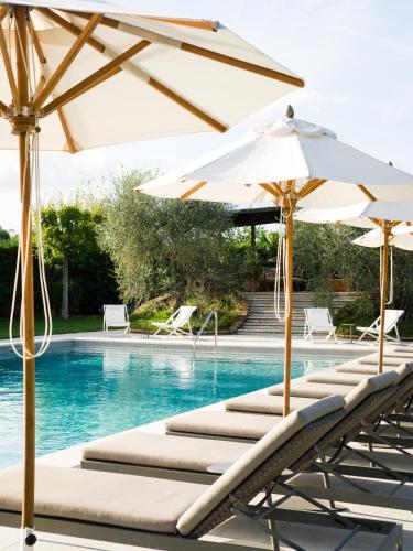 a row of lounge chairs with umbrellas next to a swimming pool at Borgo San Vincenzo in Montepulciano