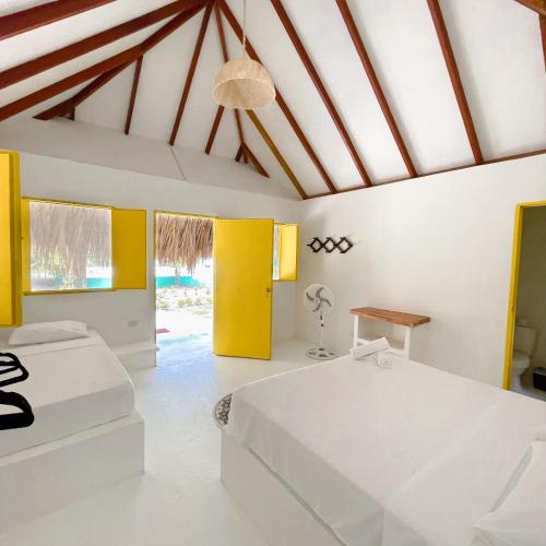 a bedroom with two beds and a ceiling with beams at Hotel Coral Sand Islas Del Rosario in Isla Grande