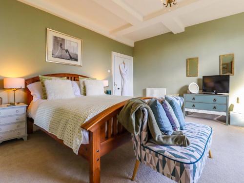 a bedroom with a bed and a tv and a couch at Goss Hall in Canterbury