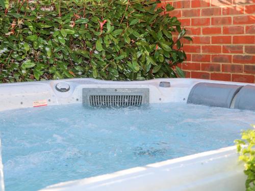 a jacuzzi tub in a yard next to a brick wall at Goodwood Retreat in Chichester
