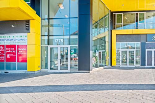 a yellow building with glass doors on a street at Bright Suites Finch West steps to Metro in Toronto