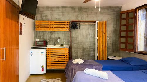 a small room with two beds and a refrigerator at Maloca Hospedagem in Sao Jorge