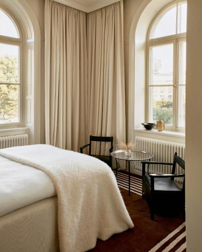 a bedroom with a bed and a table and windows at Stockholm Stadshotell in Stockholm