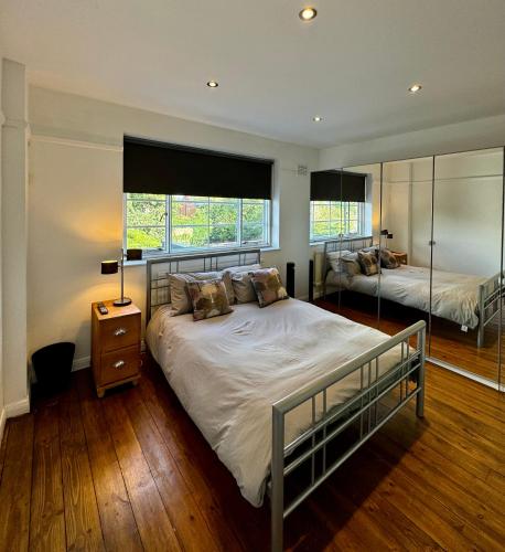 a bedroom with a large bed and two windows at Spacious 4 beds house with FAST WIFI and FREE PARKING ideal for businesses, visiting family or relocation in Hatfield