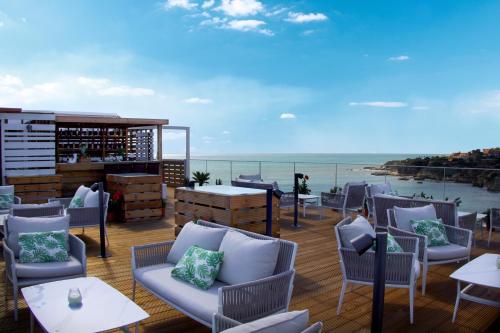 a patio with chairs and tables and a view of the ocean at Monicca Collection Suites and Residences in Albufeira