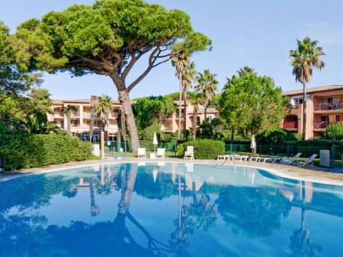 une piscine avec un arbre et un bâtiment dans l'établissement T3 Vue mer les pieds dans l'eau, piscine, clim, à Hyères