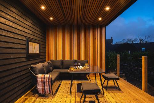 a patio with a couch and a table on a deck at POD St Ives - LUXURY GLAMPING ACCOMMODATION in St Ives