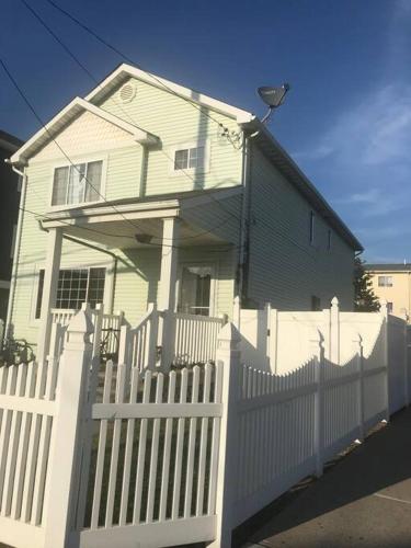 a white fence in front of a white house at Private BR,BA,KIT, LR 9 Mins to Beach in Edgemere