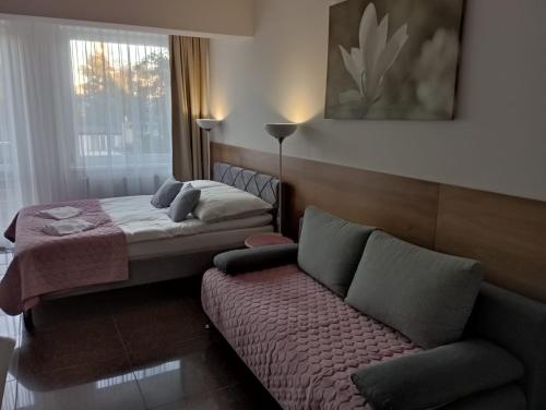 a bedroom with a bed and a couch and a window at Apartamenty Planeta 105, 108 Mielno - parking w cenie pobytu in Mielno