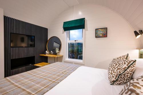 a bedroom with a bed and a tv and a window at POD St Ives - LUXURY GLAMPING ACCOMMODATION in St Ives