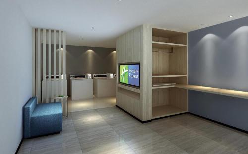 a waiting room with a tv and a blue chair at Holiday Inn Express Zhangye by IHG in Zhangye