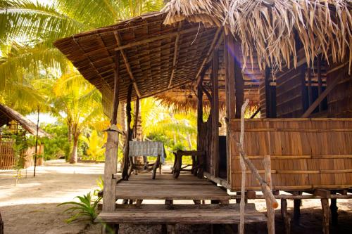 a straw hut with a bench and a chair on a porch at manyaifun guest house in Minyaifuin