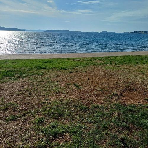 a field of grass next to a body of water at Vila Matias in Vodice