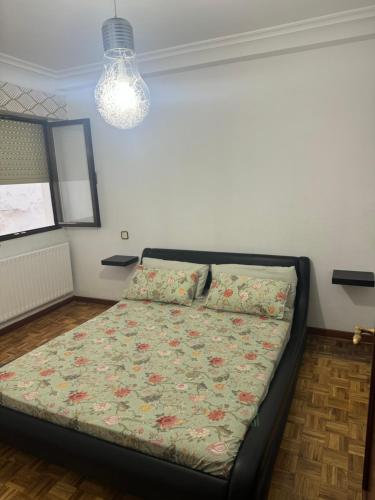 a bedroom with a bed with a floral comforter at RENFE-ALSA y clinicas in Oviedo