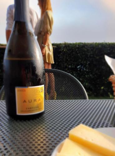a bottle of wine sitting on a table with cheese at Agriturismo B&B Casa Bortolin in Valdobbiadene