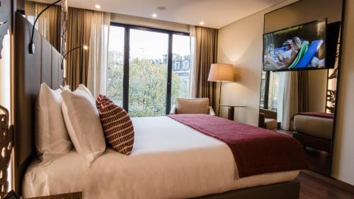 a hotel room with a bed and a flat screen tv at TURIM Oporto Hotel in Porto